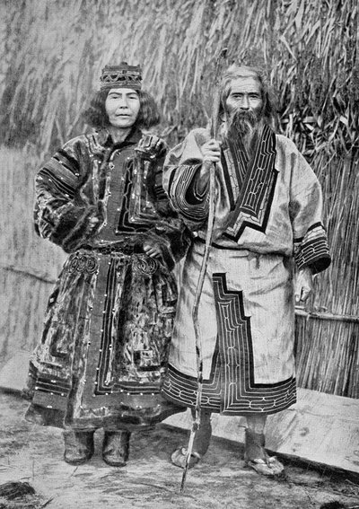 Ainu-Paar vor dem traditionellen Ainu-Haus einer Schilfrohrhütte, späte 19. Jahrhundert von Messrs. Kajima and Suwo